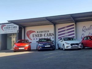 Eine Außenaufnahme eines Autohändlers namens Ramstein Used Cars mit vier parkenden Autos davor.