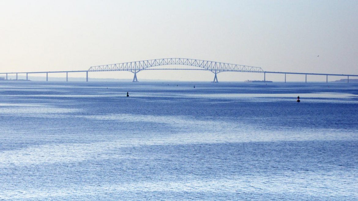 Weitläufige Ansicht einer langen Brücke, die über ein großes Gewässer spannt, unter einem klaren, blauen Himmel.