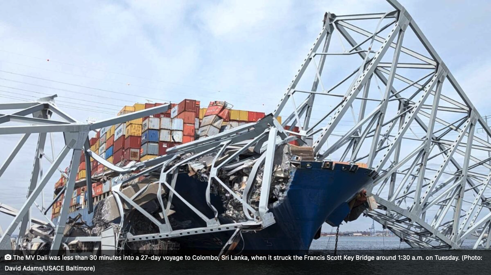 Ein Frachtschiff ist in eine Brücke kollidiert, wodurch Teile der Brücke stark beschädigt wurden und Container gestapelt sind.